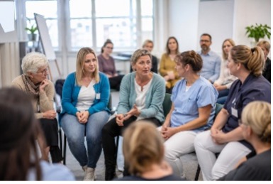 Mitarbeitende im Halbkreis sitzend - miteinander im Gespräch